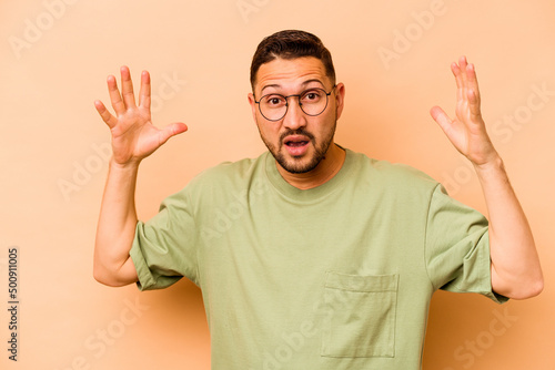 Young hispanic man isolated on beige background celebrating a victory or success, he is surprised and shocked. © Asier