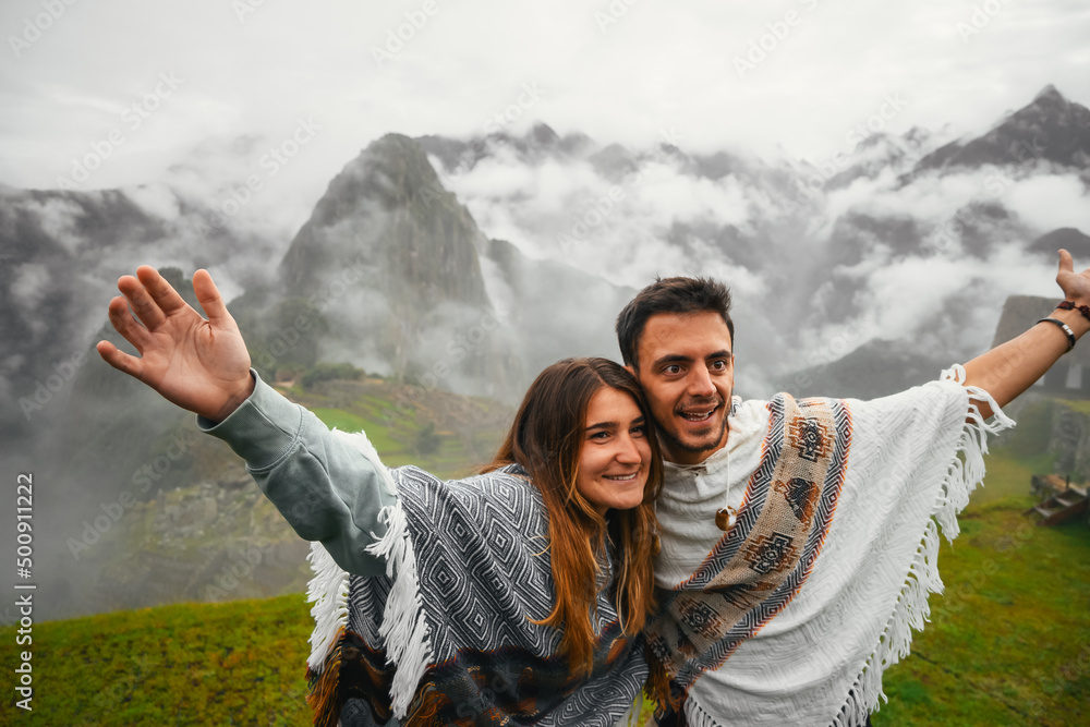 Portrait of a smiling caucasian couple wearing the traditional peruvian poncho in Machu Picchu.