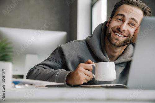Young beard man drinking coffee while working with laptop