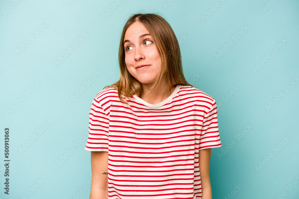 Young caucasian woman isolated on blue background laughs and closes eyes, feels relaxed and happy. Young caucasian woman isolated on blue background laughs and closes eyes, feels relaxed and happy.