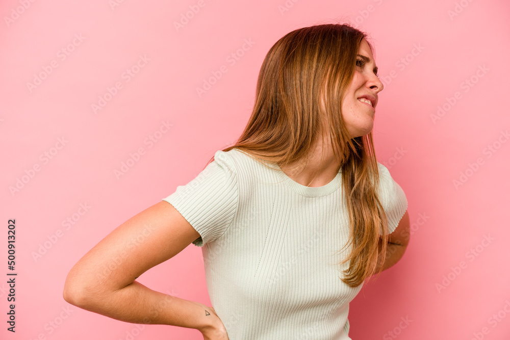 Young caucasian woman isolated on pink background suffering a back pain. Young caucasian woman isolated on pink background suffering a back pain.