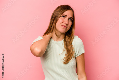 Young caucasian woman isolated on pink background having a neck pain due to stress, massaging and touching it with hand.