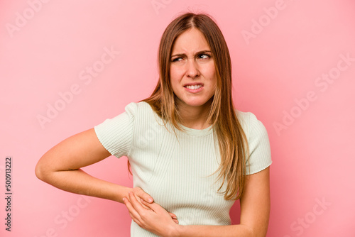 Young caucasian woman isolated on pink background having a liver pain, stomach ache.