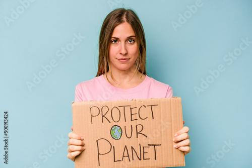 Young caucasian woman holding protect your planet placard isolated on blue background © Asier