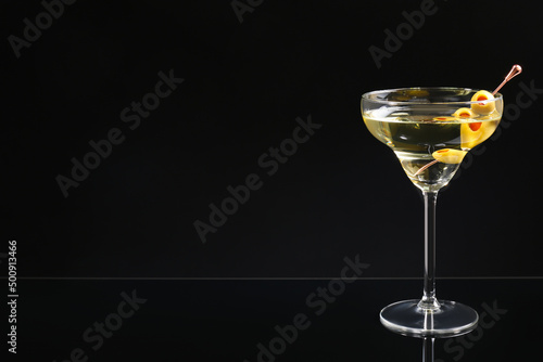 Martini cocktail with olives on dark background, space for text