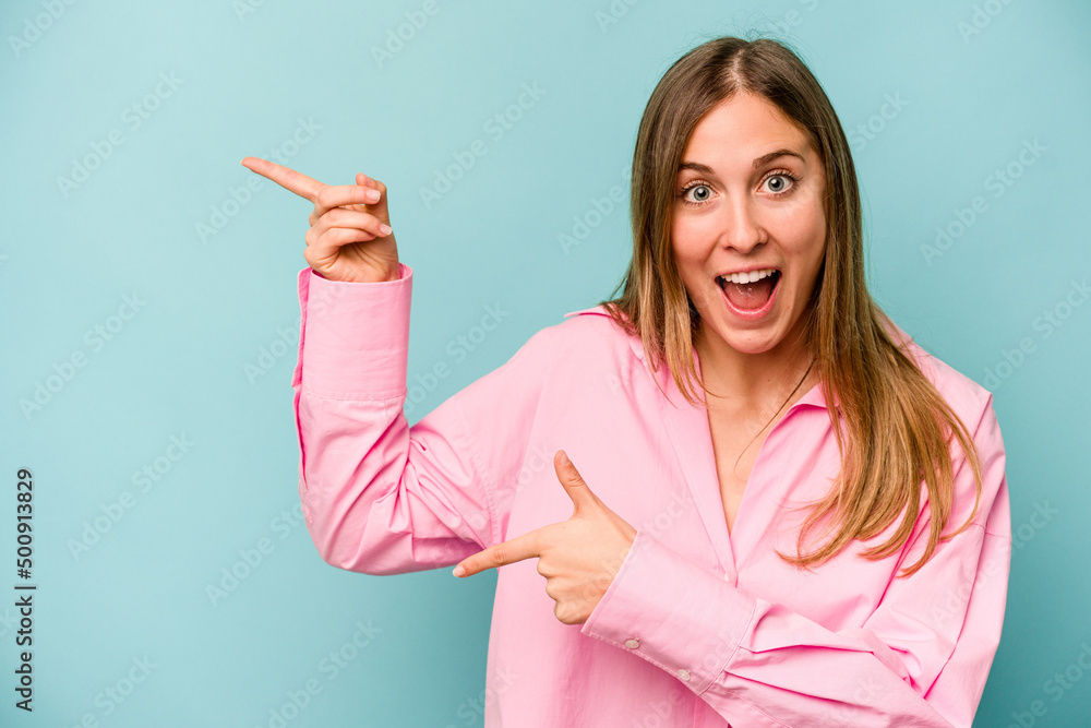Young caucasian woman isolated on blue background excited pointing with forefingers away. Young caucasian woman isolated on blue background excited pointing with forefingers away.