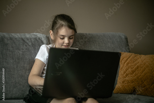 Dziecko bawiące się laptopem na kanapie