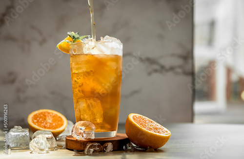 fresh home made orange lemonade or kombucha in tall glass over grey background, healthy eating, detox, wellbeing concept photo