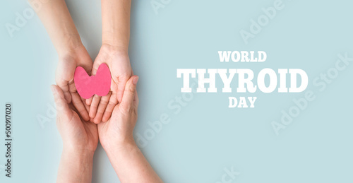 World Thyroid Day. Adult and children holding paper form of the thyroid gland on blue background. Problems with thyroid. Polycystic disease. World cancer day