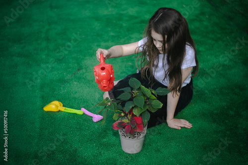 Młoda dziewczyna podlewająca kwiata w doniczce