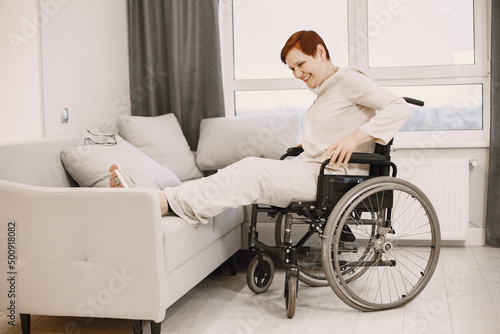 Senior woman trying to sit down in wheelchair from couch