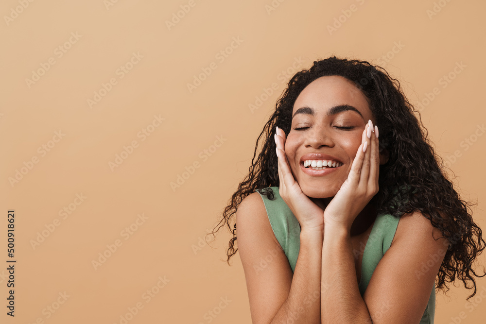Fototapeta premium Young black woman touching her face and smiling at camera
