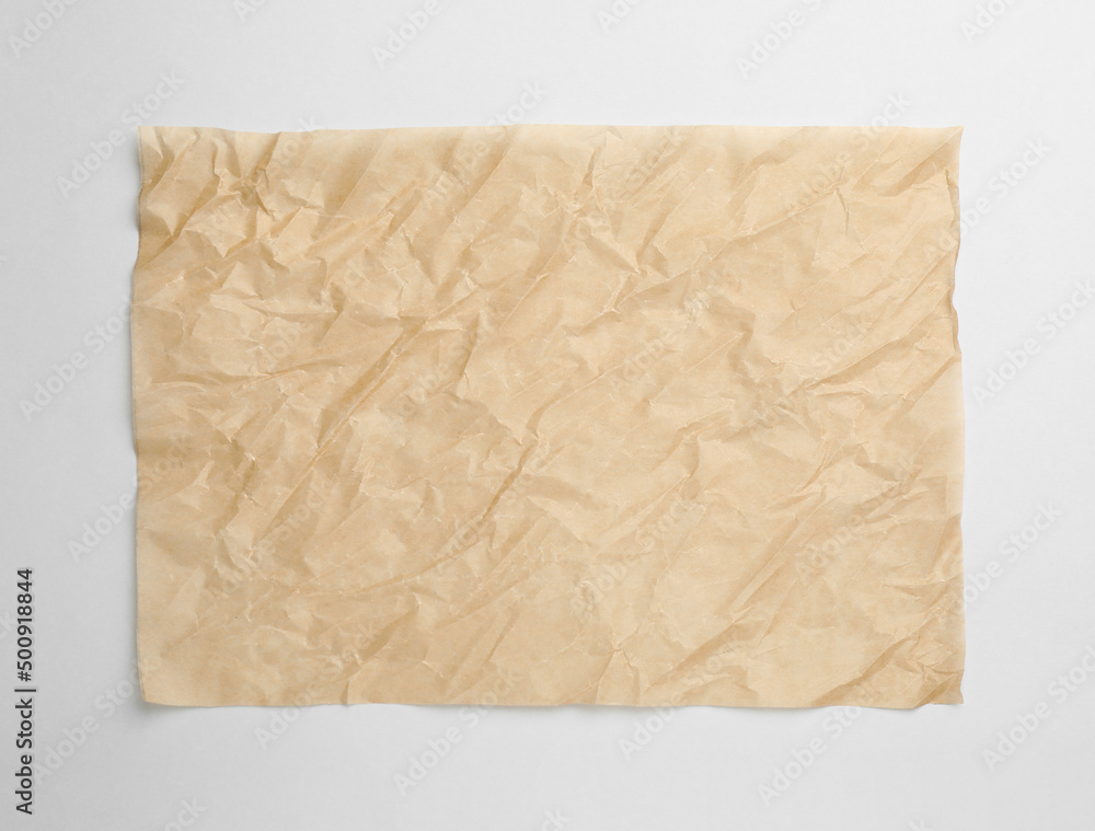 Sheet of crumpled brown baking paper on white background, top view Sheet of crumpled brown baking paper on white background, top view