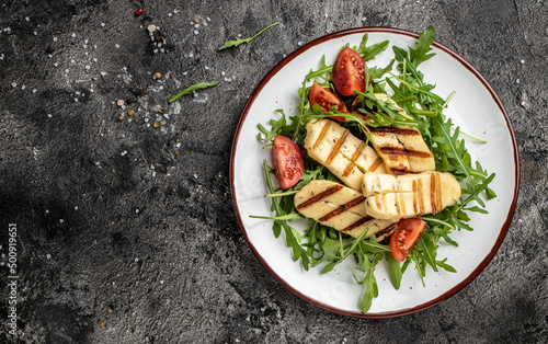halloumi cheese salad with arugula and tomatoes. ketogenic paleo diet. Delicious breakfast or snack, Clean eating, dieting, vegan food concept. top view photo