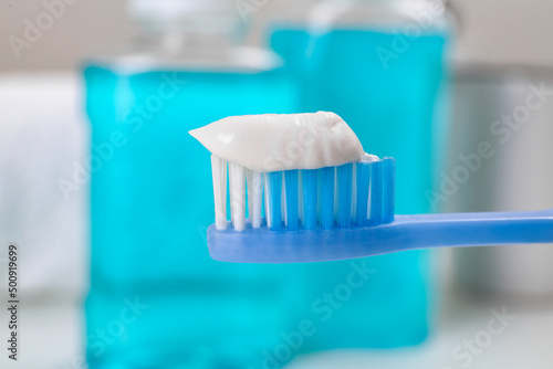 Fototapeta Naklejka Na Ścianę i Meble -  Toothbrush with paste near mouthwash on blurred background, closeup