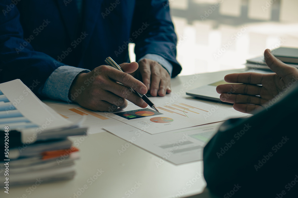 2 businessmen with pens pointing to financial charts for analysis Discuss planning colleagues in meetings and successful teamwork. 2 businessmen with pens pointing to financial charts for analysis Discuss planning colleagues in meetings and successful teamwork.