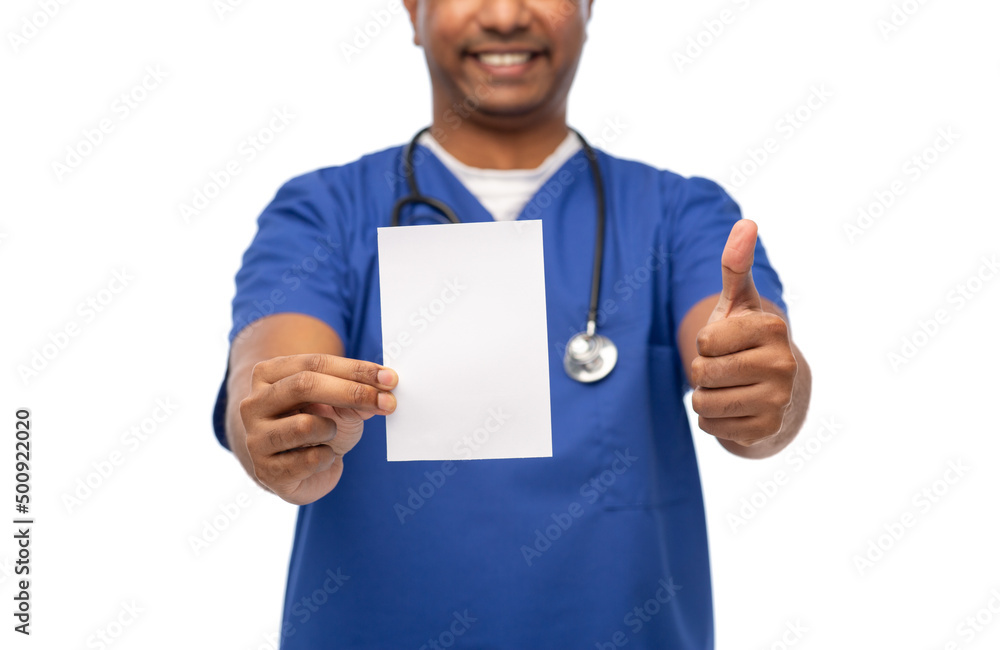 healthcare, profession and medicine concept - close up of happy smiling doctor or male nurse in blue uniform with stethoscope showing white paper and thumbs up gesture over white background healthcare, profession and medicine concept - close up of happy smiling doctor or male nurse in blue uniform with stethoscope showing white paper and thumbs up gesture over white background