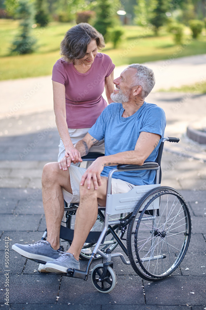 A man in a wheel chair and his wife on a walk in the park
