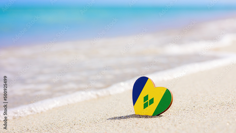 Obraz premium Flag of Saint Vincent and the Grenadines in the shape of a heart on a sandy beach. The concept of the best vacation in Saint Vincent and the Grenadines resorts