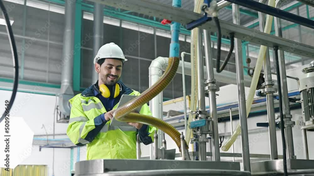 Mechanical engineer with tablet checking condition of storage tank and pipeline for observe abnormal operating status in beverage production plant Mechanical engineer with tablet checking condition of storage tank and pipeline for observe abnormal operating status in beverage production plant