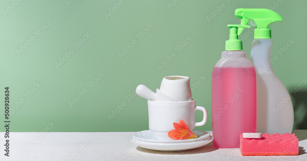 white tableware and kitchen cleaning detergents on a table. housekeeping and householding, spring cleaning concept. white tableware and kitchen cleaning detergents on a table. housekeeping and householding, spring cleaning concept.