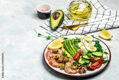 shrimps, prawns, soft fried egg, fresh salad, tomatoes, cucumbers and avocado on a light background. Ketogenic diet breakfast. Keto, paleo lunch. Top view