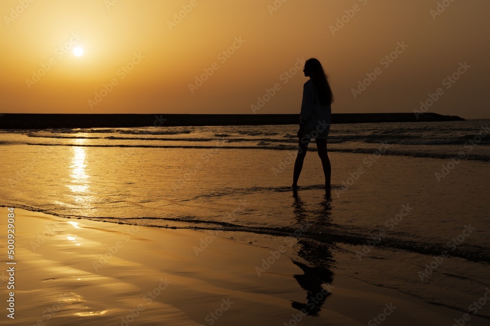 Silhouette of a woman against the sunset over the sea