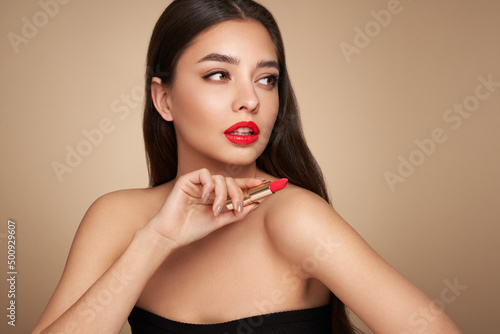 A beautiful young woman applying lipstick. Model with healthy skin, close up portrait. Cosmetology, beauty and spa