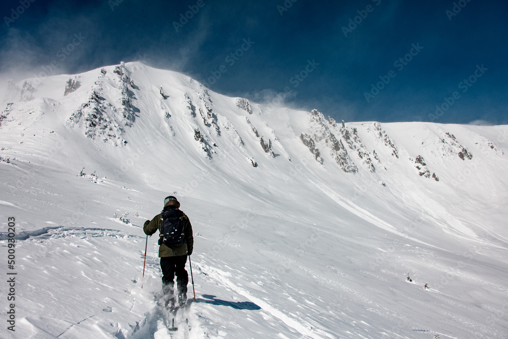 rear view of skier with backpack going up the snowy mountain