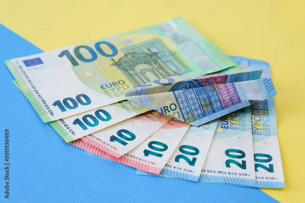 Paper plane from euro banknotes on a blue-yellow background Paper plane from euro banknotes on a blue-yellow background