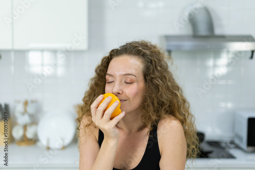 inspiration of smart healthy woman smelling orange in hand before mixing healthy fruit juice in kitchen with copy space. beautiful caucasian woman cooking healthy diet fruit or vegetable in kitchen