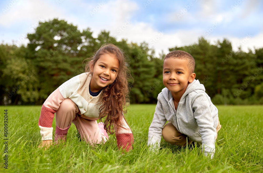 childhood, leisure and people concept - happy smiling little boy and girl having fun at park childhood, leisure and people concept - happy smiling little boy and girl having fun at park