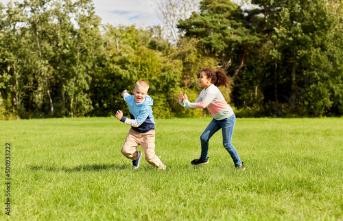 childhood, leisure and people concept - happy children playing tag game and running at park