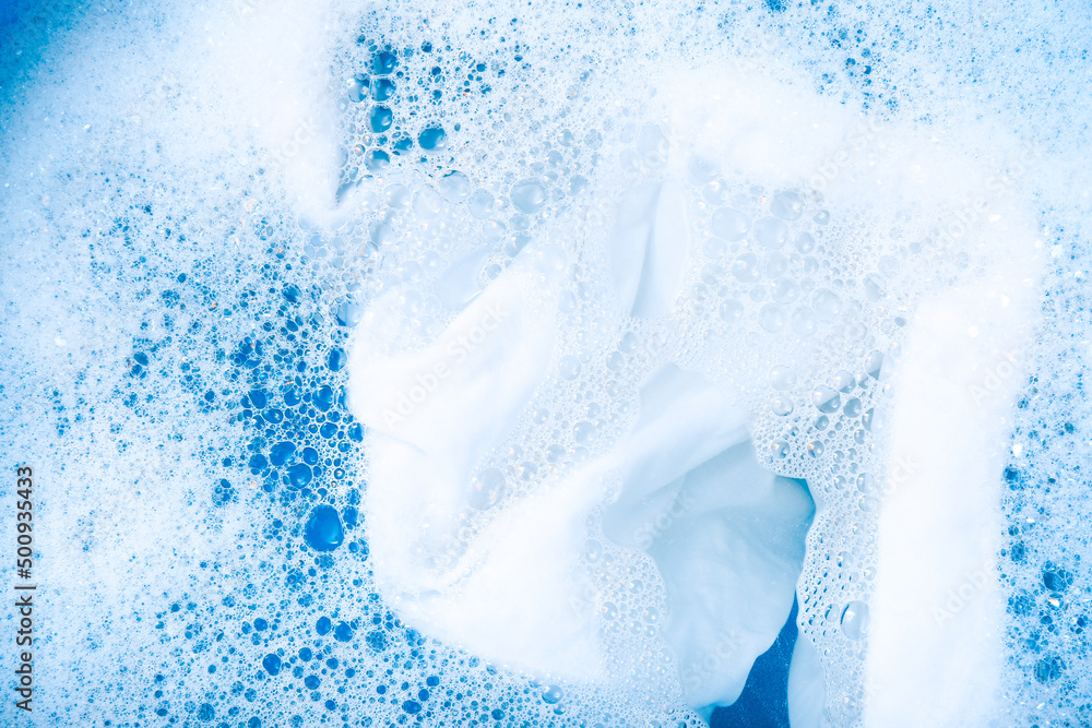 White garment in suds, closeup. Hand washing laundry White garment in suds, closeup. Hand washing laundry