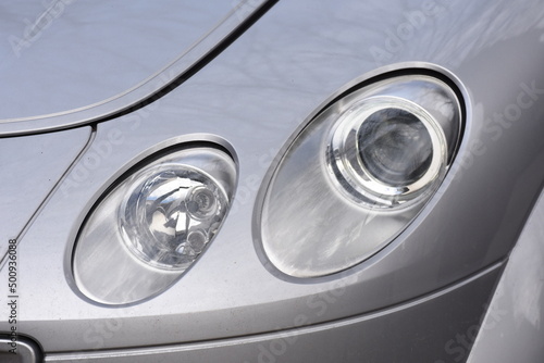 shiny headlights on a gray car © Laurenx