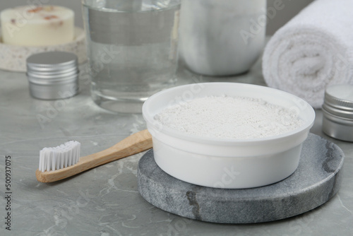 Tooth powder and brush on light grey marble table, closeup