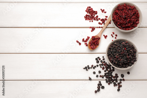 Dried red and black currant berries on white wooden table, flat lay. Space for text