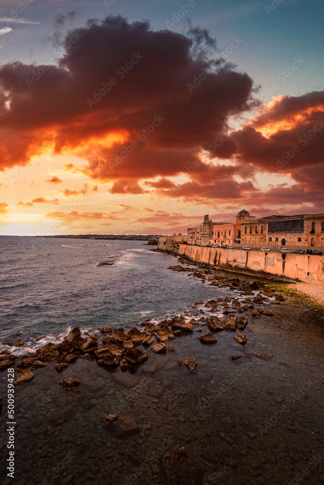 Spectacular red sunset on the sea with Maniace castle in Ortigia