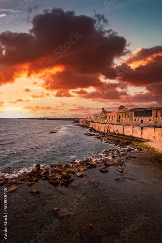 Spectacular red sunset on the sea with Maniace castle in Ortigia