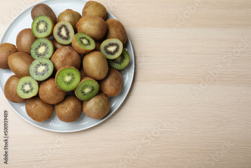 Fresh ripe kiwis on light wooden table, top view. Space for text