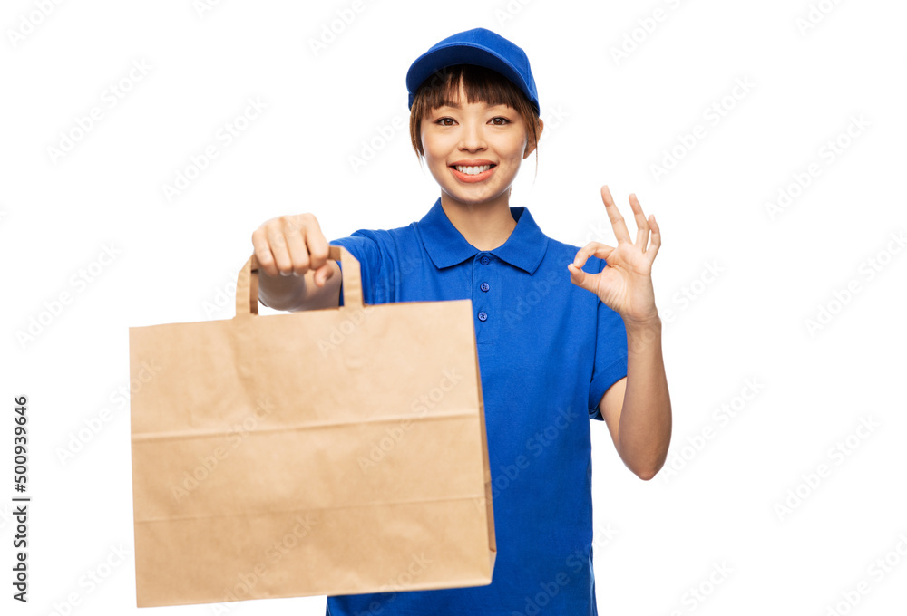 service and job concept - happy smiling delivery woman in blue uniform with takeaway food in paper bag showing ok gesture over white background service and job concept - happy smiling delivery woman in blue uniform with takeaway food in paper bag showing ok gesture over white background