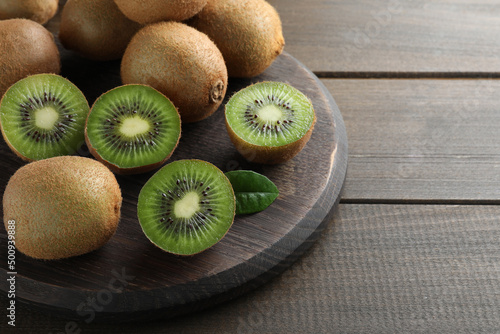 Fresh ripe kiwis on wooden table, space for text