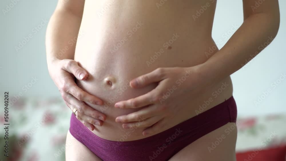 Pregnant woman stroking her belly with hands Pregnant woman stroking her belly with hands