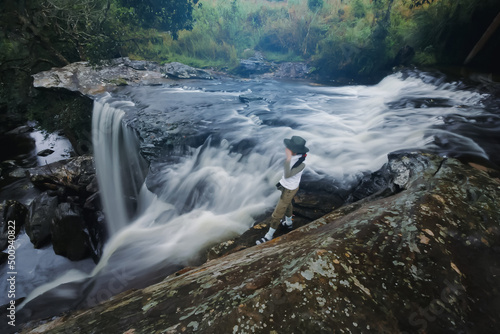 Woman and nature - Penpobmai Waterfall - Phu Kradueng National Park. It is a sandstone mountain peak cut. It has a high point of 1,316 m. The mountain’s steep sides are home of tropical forest. photo