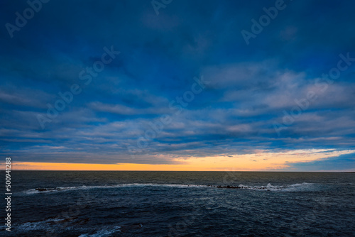 Sunset over the sea with cloudy sky and sun glow in the background