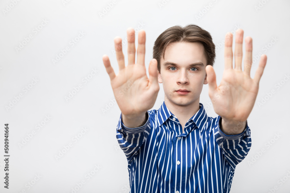 Young man showing stop gesture studio shot on gray background Young man showing stop gesture studio shot on gray background