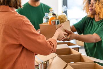 charity, donation and volunteering concept - close up of volunteers giving box of food at distribution or refugee assistance center