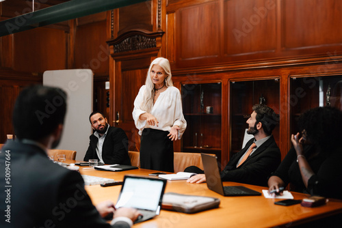 Confident businesswoman discussing with lawyers in board room during conference meeting