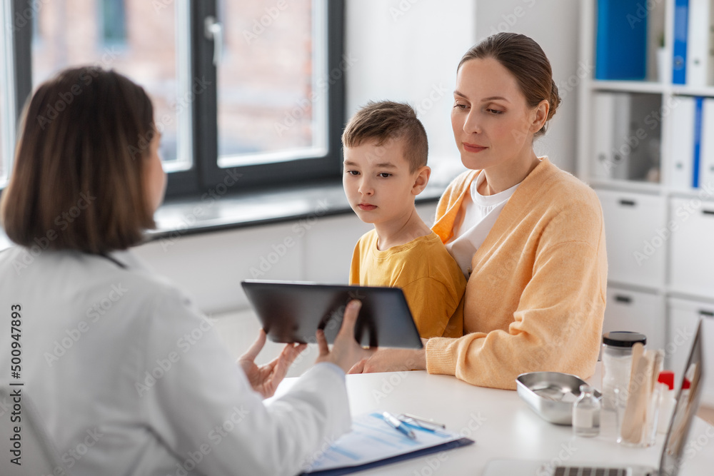 medicine, healthcare and pediatry concept - smiling mother with little son and doctor with tablet pc computer at clinic medicine, healthcare and pediatry concept - smiling mother with little son and doctor with tablet pc computer at clinic