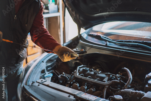 Mechanic wipes the engine oil level dipstick.